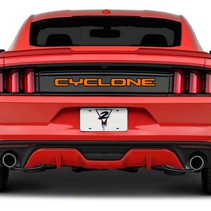 May include: Rear view of a red Ford Mustang with a black rear bumper and black taillights. The car has a black license plate with the word "CYCLONE" in orange letters on the rear.