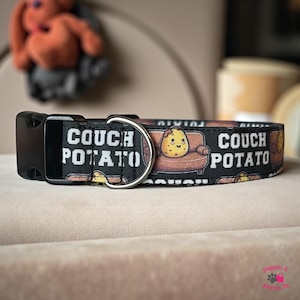 Puede incluir: Collar negro para perros con las palabras "COUCH POTATO" en letras blancas. El collar presenta un patrón repetido de una patata de dibujos animados en un sofá. El collar tiene una hebilla de plástico negro y una anilla en D de metal plateado.
