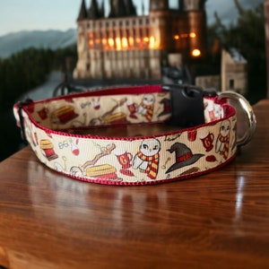 May include: A cream-colored dog collar with a repeating pattern of owls, hats, and other magical icons. The collar has a burgundy trim and a black plastic buckle with a silver metal loop.