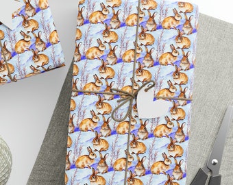 May include: Two gift boxes wrapped in blue and white wrapping paper with a pattern of brown rabbits. The wrapping paper has a watercolor look. The boxes are tied with twine and have white gift tags attached.