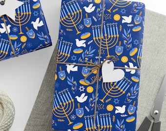 Puede incluir: Tres cajas de regalo azules con temática de Hanukkah. Las cajas están envueltas en papel con un patrón repetido de menorás, dreidels, estrellas de David y palomas. Las cajas están atadas con cordel y tienen etiquetas de papel blanco.