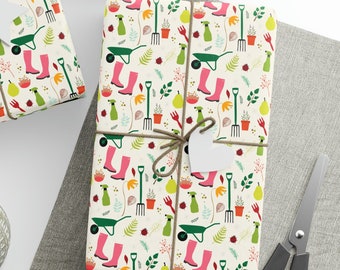 Puede incluir: Una hoja de papel de regalo blanco con un patrón repetido de botas rosas, carretillas verdes y herramientas de jardinería. El papel está atado con cuerda y tiene una etiqueta de regalo blanca.