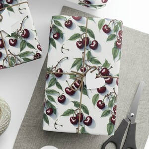 May include: Three white gift boxes with a cherry print design. The boxes are wrapped with twine and have white paper tags with a star and heart shape.