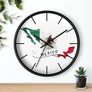 May include: Black wall clock with a white face and black hands. The clock face features a map of Mexico with the Mexican flag colours and the word "MEXICO" in white text.