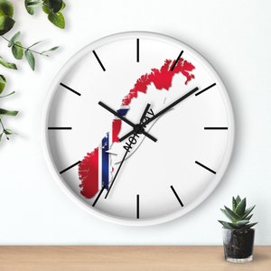May include: White wall clock with black hands and a map of Norway with the Norwegian flag colours on it. The clock says "NORWAY" on it.