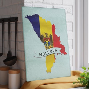 May include: A light blue glass chopping board with a map of Moldova in the shape of the country's flag. The flag is yellow, blue, and red with the country's coat of arms in the centre. The word "MOLDOVA" is written in white on a white ribbon.