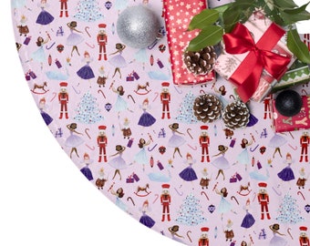 Puede incluir: Una falda de árbol de Navidad rosa con un patrón de Cascanueces y bailarina. La falda está decorada con adornos, bastones de caramelo y caballitos de balancín. También hay regalos envueltos con patrones de estrellas rojas y blancas encima de la falda.
