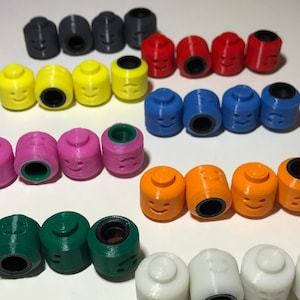 May include: A collection of colourful plastic face figurines with different expressions. The figurines are arranged in rows, with each row featuring a different colour. The colours include black, yellow, red, blue, pink, green, orange, and white.
