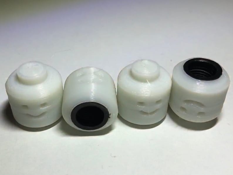May include: Four white plastic toy heads with different facial expressions. Each head has a black plastic ring around the bottom.