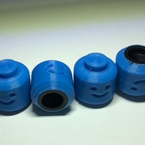 May include: Four blue plastic bottle stoppers with different smiley faces. Each stopper has a black threaded insert.