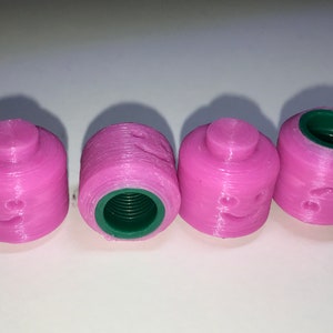 May include: Four pink plastic bottle caps with a green interior and a smiley face design.