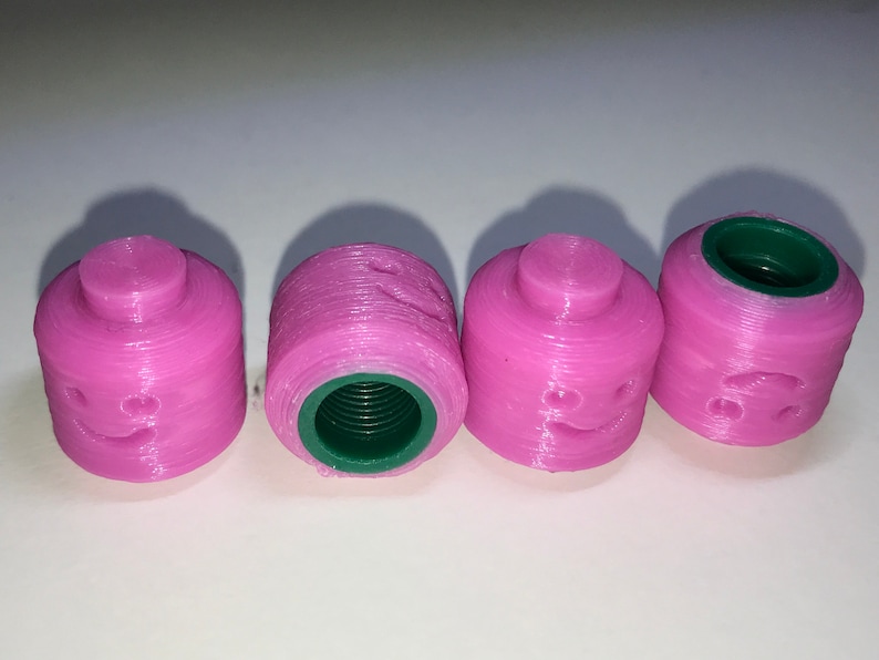 May include: Four pink plastic bottle caps with a green interior and a smiley face design.
