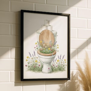 Könnte beinhalten: Ein gerahmter Aquarelldruck zeigt eine Toilette, die mit Wildblumen überquillt. Der Toilettensitz ist aus Holz, und Toilettenpapierrollen liegen auf dem Tank. Das Kunstwerk ist vor einem weißen Fliesen Hintergrund dargestellt.