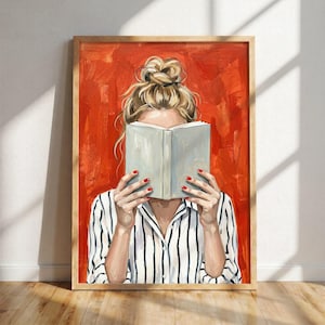 May include: A framed art print featuring a person with blonde hair in a messy bun, wearing a white shirt with vertical black stripes, holding an open light grey book in front of their face against a textured, vibrant orange-red painted background.