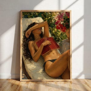 May include: A framed art print depicts a person reclining on a lounge chair, holding a red book. The person is sunbathing, with their eyes covered by their arm. Lush greenery and flowers are in the background, with a wooden frame.