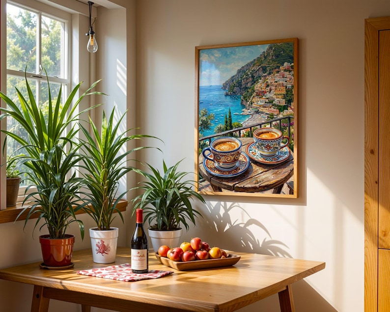 Puede incluir: Un cuadro de pared enmarcado que representa dos tazas de caf&eacute; sobre una mesa de madera con vistas a una ciudad costera, expuesto sobre una mesa de madera con tres plantas en macetas, una botella de vino tinto y un cuenco de madera con frutas.