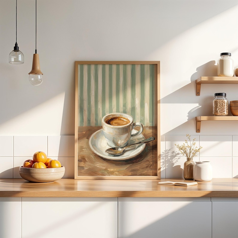 May include: A framed art print of a coffee cup on a saucer with a spoon. The painting has a light brown wooden frame and depicts a cup of coffee with a light brown crema. The background has vertical stripes of white and light green.