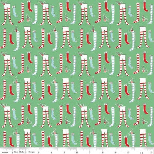 May include: A green fabric with a repeating pattern of red and white striped stockings, blue socks, and red stockings with white trim. The stockings are arranged in a symmetrical pattern.
