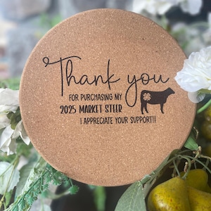 May include: A round cork coaster with the text "Thank you for purchasing my 2025 Market Steer I appreciate your support!!" and a silhouette of a cow with a four-leaf clover.