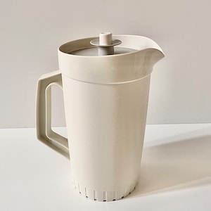 May include: A white plastic pitcher with a lid and a handle. The pitcher has a textured surface and a spout.