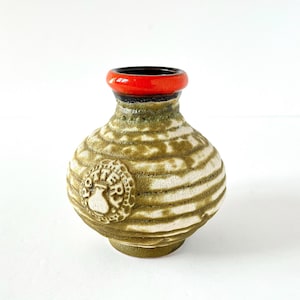 May include: A small, green and white ceramic vase with a red rim and a raised, circular design featuring the word "Potter" in a stylized font.