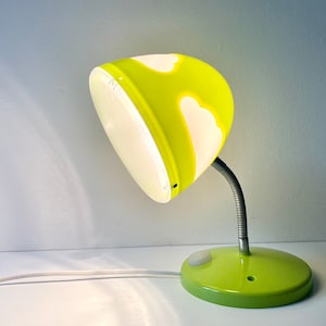 May include: A green desk lamp with a white cloud design on the shade. The lamp has a flexible arm and a white cord.