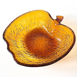 May include: Amber glass apple-shaped bowl with a textured surface.