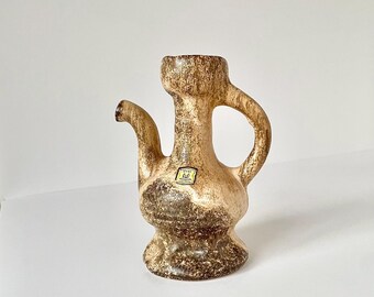 May include: A brown and white ceramic pitcher with a unique shape and a label that reads "West Germany" on the side.
