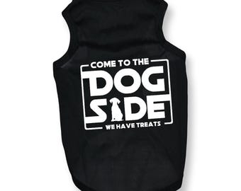 May include: Black dog tank top with white text that reads "COME TO THE DOG SIDE WE HAVE TREATS". The text is inside a white rectangle with a silhouette of a dog in the middle. The tank top is sleeveless.