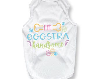 May include: White dog tank top with the text "I'm Eggstra Handsome" in colorful lettering. The design includes paw prints and Easter eggs. A fun and festive outfit for a pet.