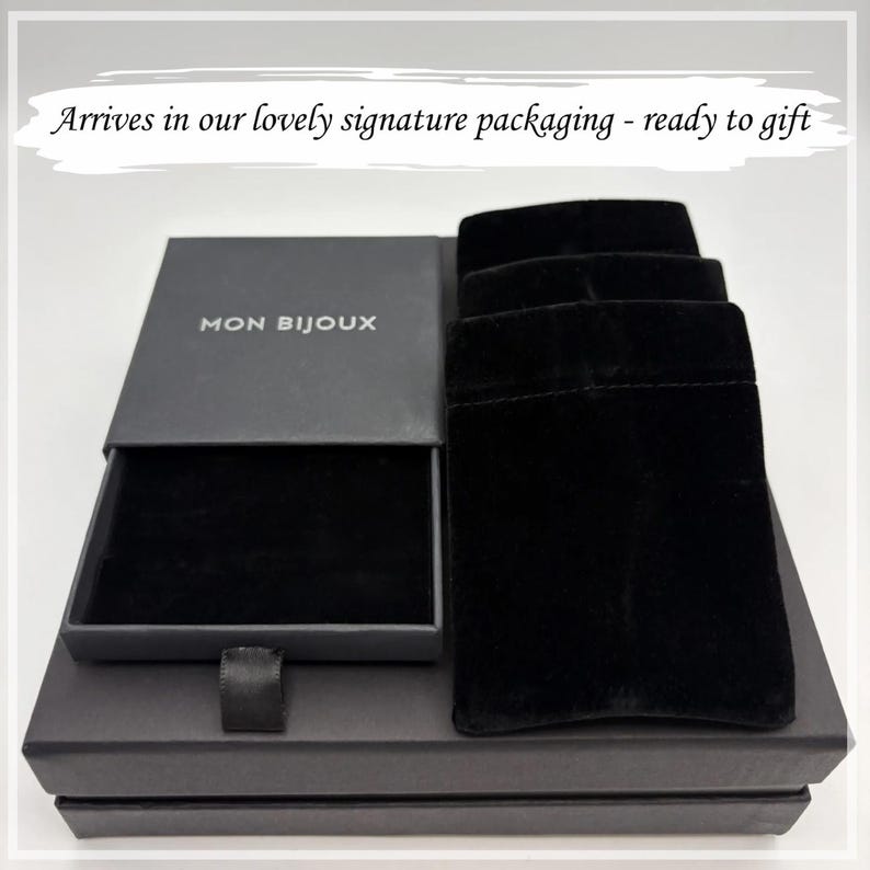 May include: A black jewellery box with the text "MON BIJOUX" on the lid, open to reveal a black velvet interior. Three black velvet pouches are next to the box. The packaging is ready to gift.