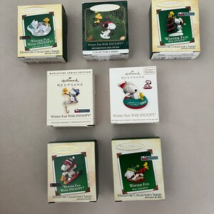 May include: Seven Hallmark Keepsake miniature collector's series boxes featuring Snoopy in winter scenes. The boxes are various colors, with Snoopy in different winter activities. The text "Winter Fun With Snoopy" is visible on the boxes.