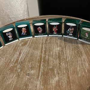 May include: A collection of eight miniature nutcracker ornaments in green and red boxes. Each box features a different nutcracker design and the text "Keepsake Ornaments Collector's Series".