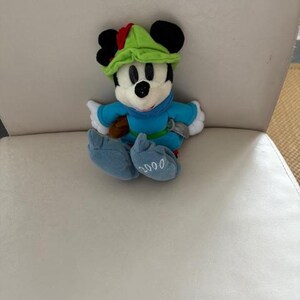 May include: A white ceramic mug with a black handle and the text "But First, Coffee" in a bold, black font. The mug is set against a blurred background, suggesting a cozy setting.