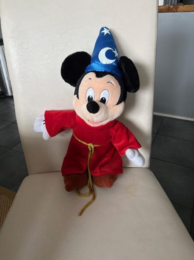 May include: A white ceramic mug with a black handle and the text "But First, Coffee" in a bold, black font. The mug is set against a neutral background, highlighting its simple design.