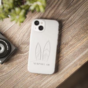 May include: White phone case with a design of two surfboards and the text "NEWPORT, OR".