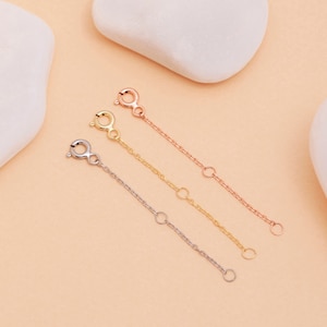May include: Three gold chain extenders, one in yellow gold, one in white gold, and one in rose gold. Each extender has a lobster clasp and is approximately 2 inches long.