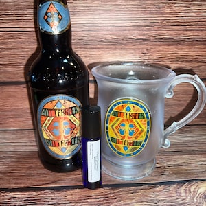 May include: A glass mug with a gold and blue Butterbeer logo, a brown glass bottle of Butterbeer, and a small blue bottle of Butterbeer essential oil.