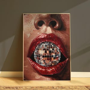 May include: A framed artwork depicting a close-up of a face with red lips holding a disco ball. The painting uses a warm colour palette with shades of brown and red. The frame is gold-coloured.
