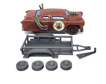 May include: A rusty red model car with a trailer and four tires. The car has a "Switchyard Studio" logo on the side. The trailer is gray and has a rectangular bed. The tires are also gray.