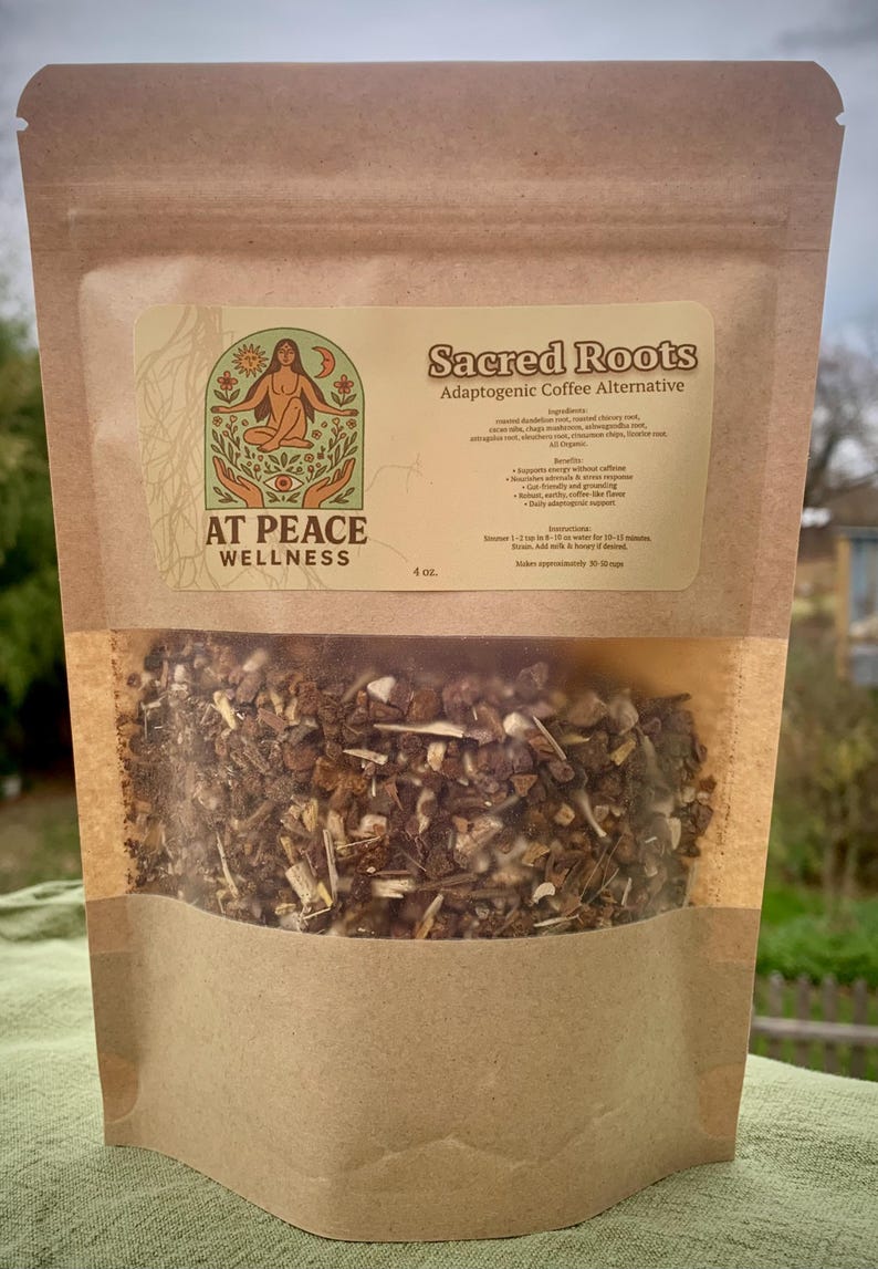 May include: A brown paper bag with a clear window, filled with a blend of dried herbs and roots. The label reads "Sacred Roots Adaptogenic Coffee Alternative" and features a logo with a woman and the words "At Peace Wellness". The bag contains 113 grams.