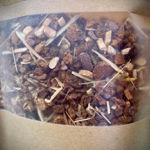 May include: A transparent bag containing a blend of dried herbs and spices. The label reads "AT PEACE WELLNESS" and "4 oz." The contents are a mix of brown, beige, and tan pieces, along with long, thin, straw-like elements. The bag is sealed.