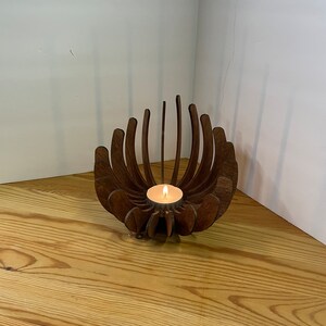 K&ouml;nnte beinhalten: Ein Kerzenhalter aus Holz in Form einer Blume mit einer kleinen Teelichtkerze in der Mitte.