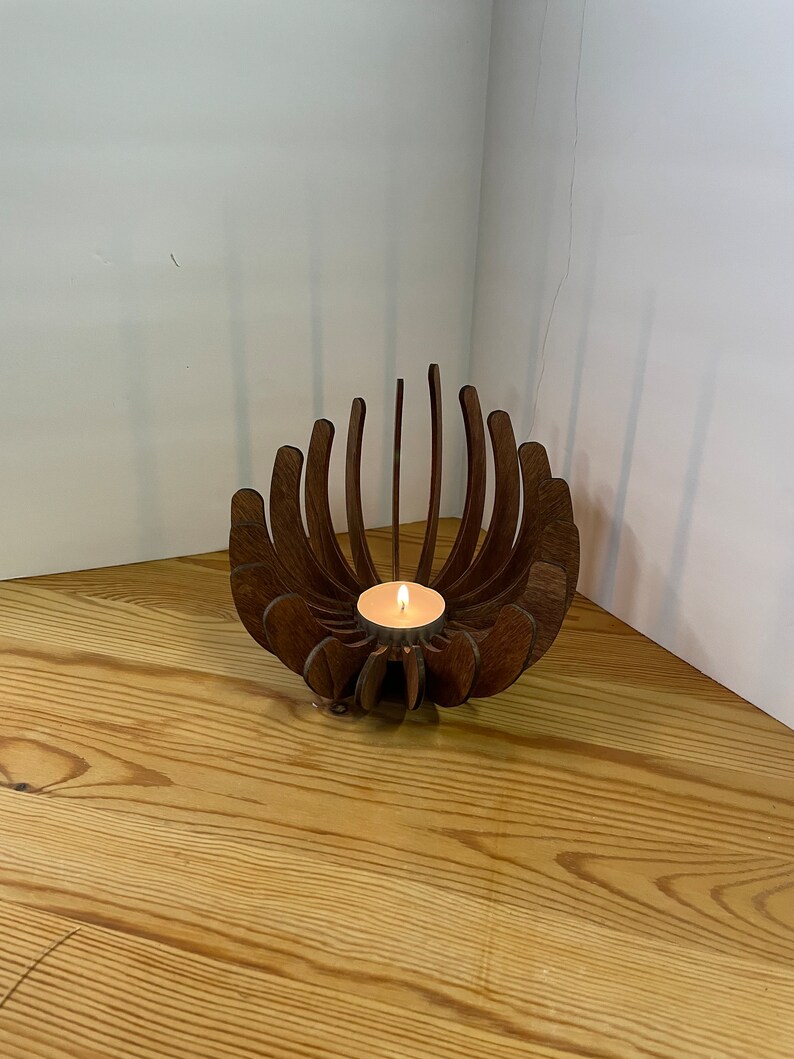 K&ouml;nnte beinhalten: Ein Kerzenhalter aus Holz in Form einer Blume mit einer kleinen Teelichtkerze in der Mitte.