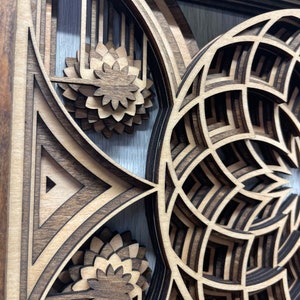 Puede incluir: Una obra de arte de madera en capas con intrincados dise&ntilde;os geom&eacute;tricos. La obra presenta una combinaci&oacute;n de madera marr&oacute;n oscura y clara, creando un efecto tridimensional. El dise&ntilde;o incluye formas florales y geom&eacute;tricas, con un enfoque en patrones en capas y cortes de precisi&oacute;n.