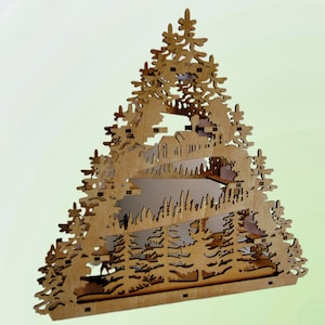 K&ouml;nnte beinhalten: Ein h&ouml;lzerner Weihnachtsbaumschmuck mit einem mehrschichtigen Design, das eine Winterszene mit H&auml;usern und B&auml;umen zeigt. Der Schmuck ist aus hellem braunem Holz gefertigt und hat eine dreieckige Form.