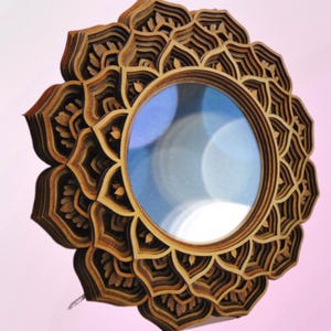 A multi-layered wooden mandala mirror with an intricate petal frame shown against a light pink background.