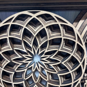 Puede incluir: Una obra de arte de madera en capas con un dise&ntilde;o floral geom&eacute;trico. La pieza est&aacute; hecha de madera marr&oacute;n clara y oscura, creando un efecto 3D. El intrincado dise&ntilde;o est&aacute; enmarcado en un marco rectangular. Adecuado para la decoraci&oacute;n de paredes.