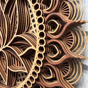 A close-up, angled view of a layered wooden lotus mandala, showing the intricate details and varying wood tones of the petals and outer rings.