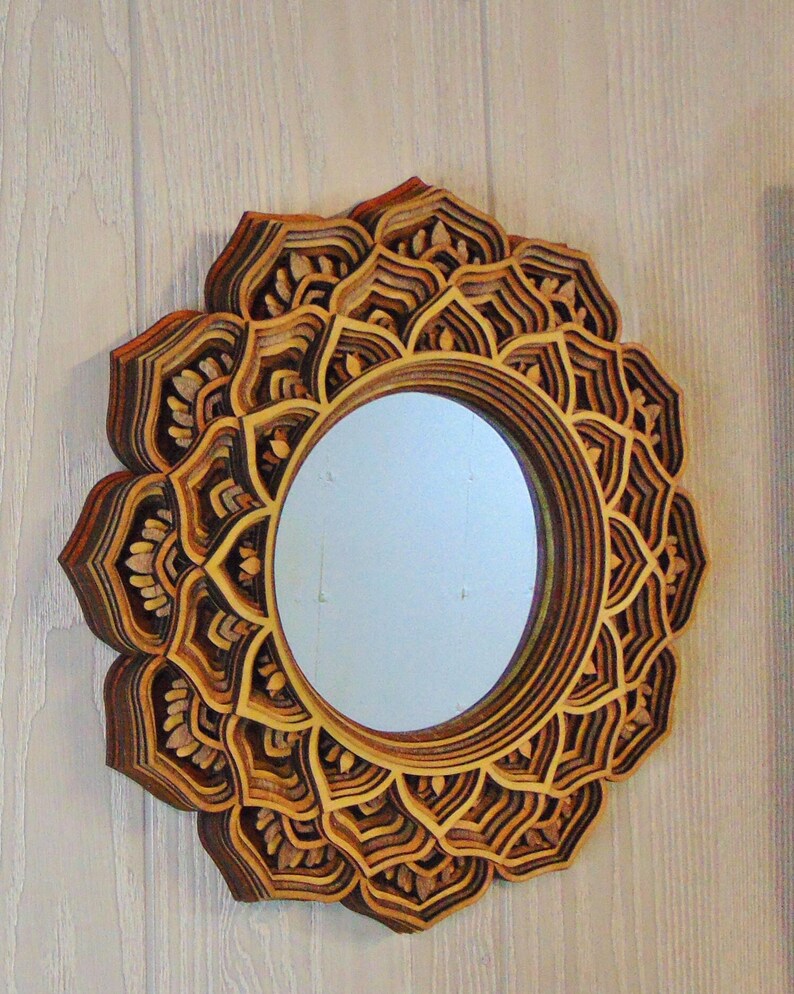A round wooden wall mirror with layered mandala flower petals hanging on a textured wall.
